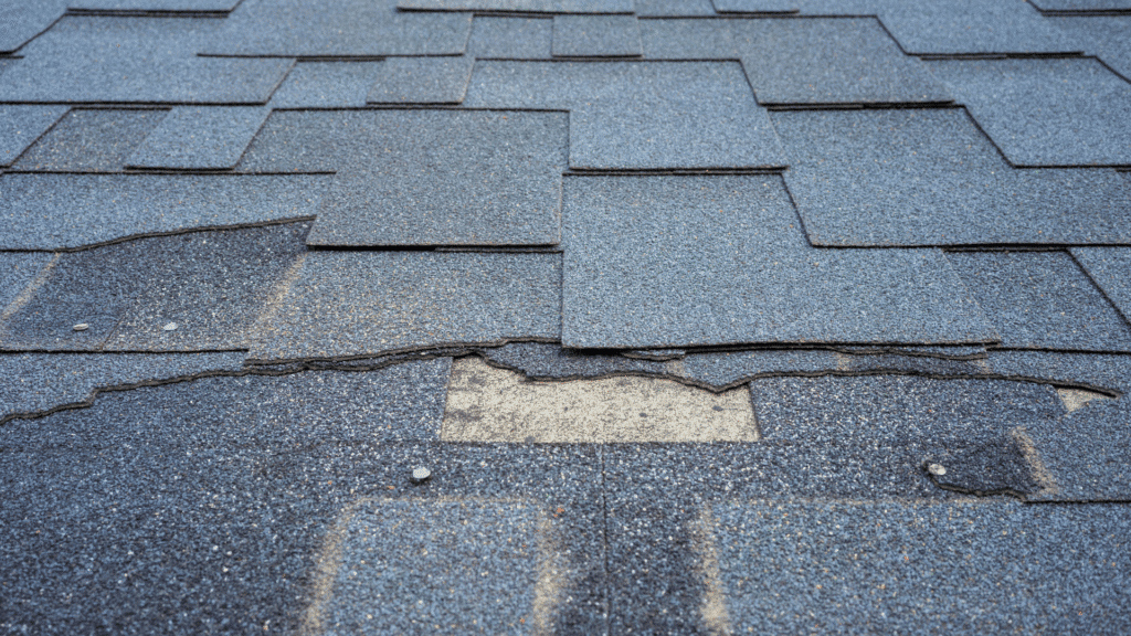 Damaged asphalt shingles on a roof with a missing piece