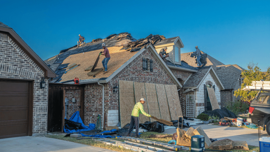 A team of roofers from Fix Roofing LLC installing new shingle material onto a large residential home during a roof replacement project.
